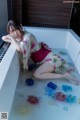 A woman in a bathtub with flowers floating in it.